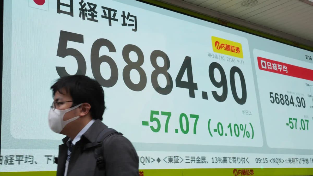 Commuter walking past large Nikkei 225 electronic market board in Japan