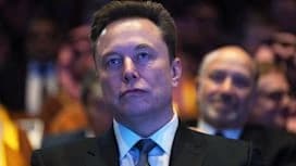 Elon Musk at a conference, looking serious, with a crowd in the background