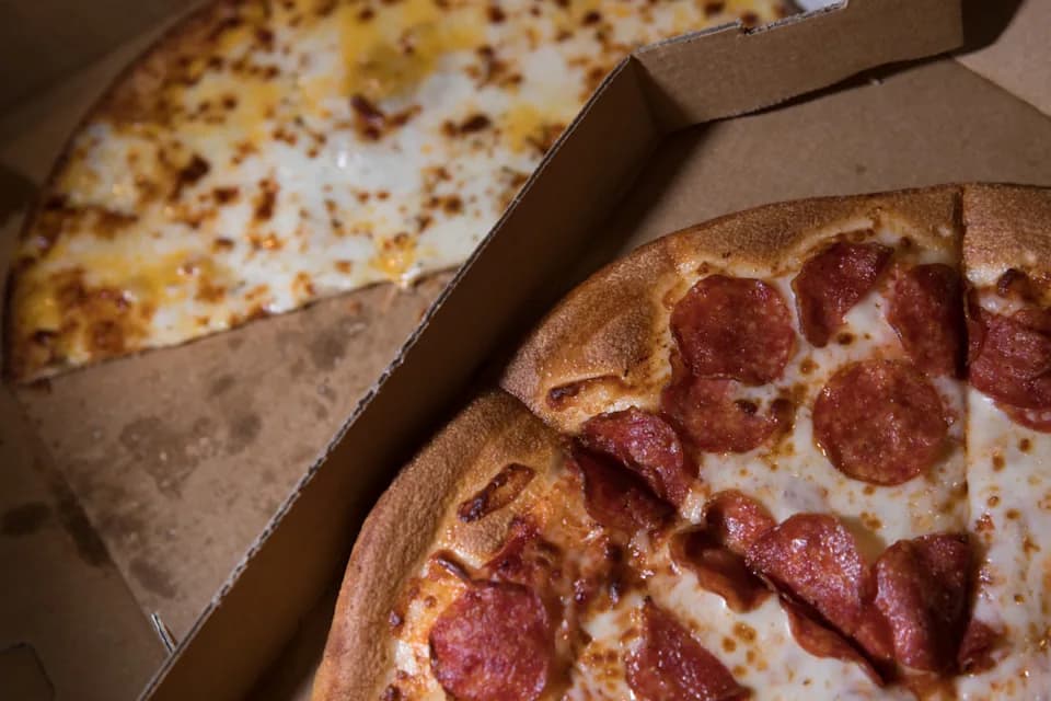 Pepperoni and cheese pizzas in open delivery boxes from Gina Maria's Pizza with melted cheese and crispy crust