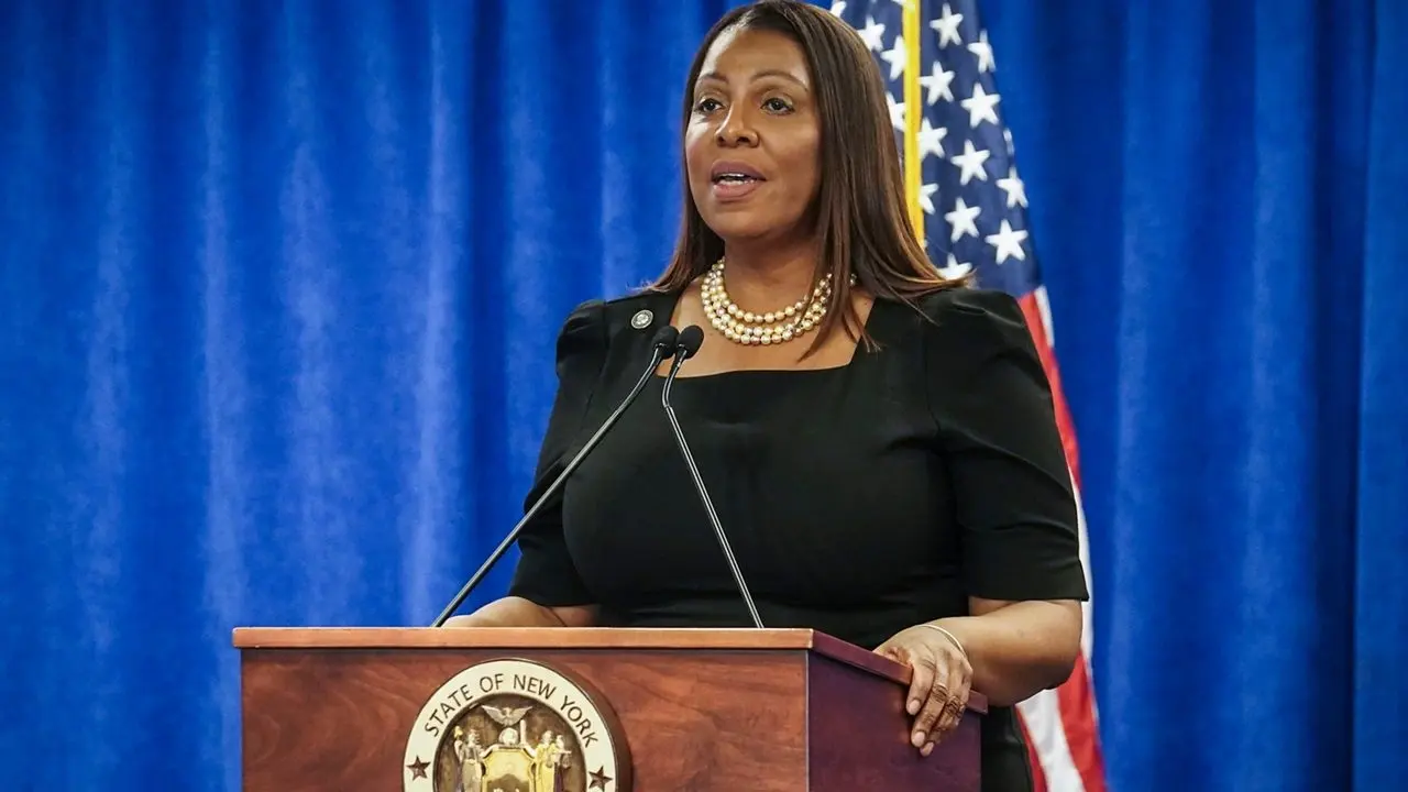 Letitia James delivering remarks at a podium during an official New York Attorney General press conference with U.S. flags in the background