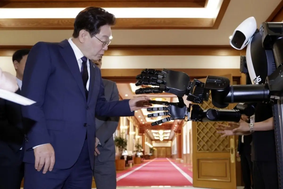 South Korean President Lee Jae Myung interacts with an AI robot while showcasing South Korea's semiconductor, artificial intelligence, and robotics investment strategy.