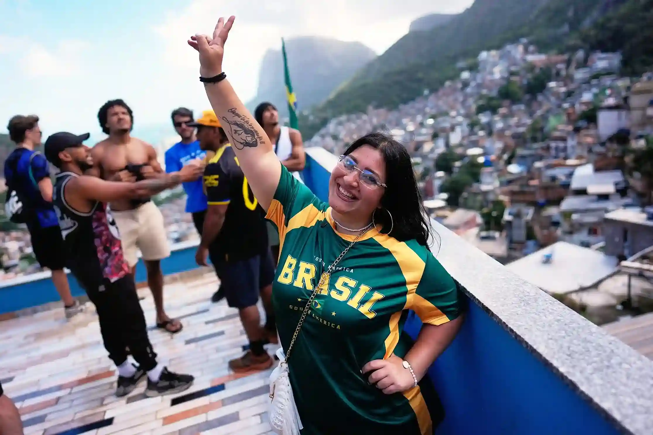 Tourists and visitors in Brazil-colored outfits taking photos at a Rio de Janeiro viewpoint overlooking the city skyline