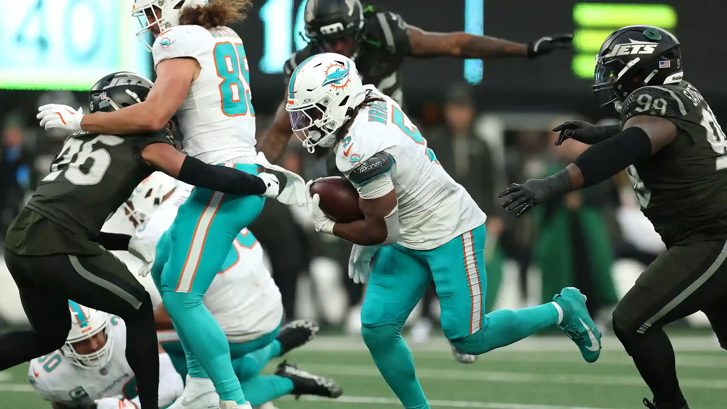 Miami Dolphins running back breaking through Jets defense during game